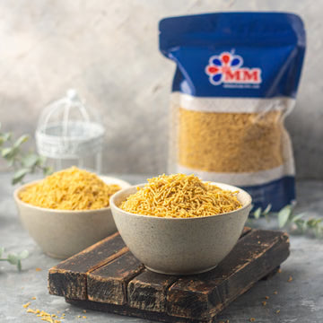 MM Mithaiwala golden Bikaneri Sev in two bowls, with its branded blue packet in the background.
