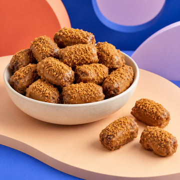MM Mithaiwala Biscoff Dates Bites with a golden crumb coating, served in a white bowl against a colourful background.