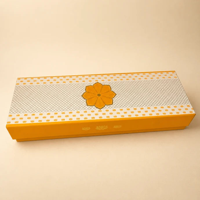 MM Mithaiwala Box Full Of Yum, a closed yellow and white rectangular gift box with a central floral motif.