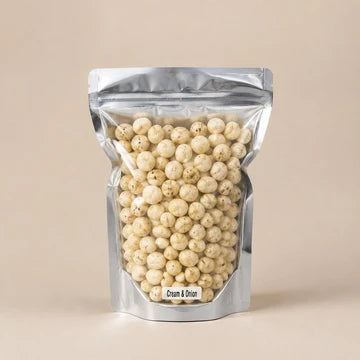 MM Mithaiwala Cream and Onion Makhana in a silver pouch showing lightly seasoned makhana through its clear front.