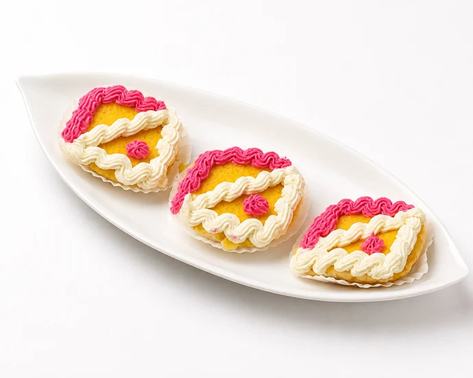 MM Mithaiwala Dilbahar sweets decorated with pink and white cream swirls, arranged on a white platter.