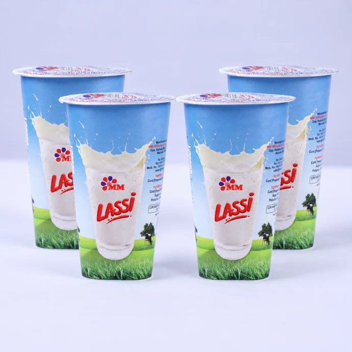 Four MM Mithaiwala Lassi cups with blue and white packaging against a pale purple background.