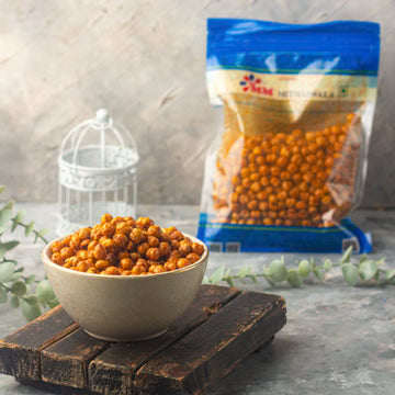 MM Mithaiwala Masala Chana served in a bowl on a wooden board, with its branded packet behind.