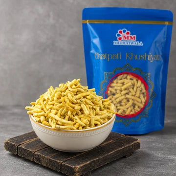 MM Mithaiwala Methi Gathiya piled in a white bowl on a wooden board beside a branded blue pouch.