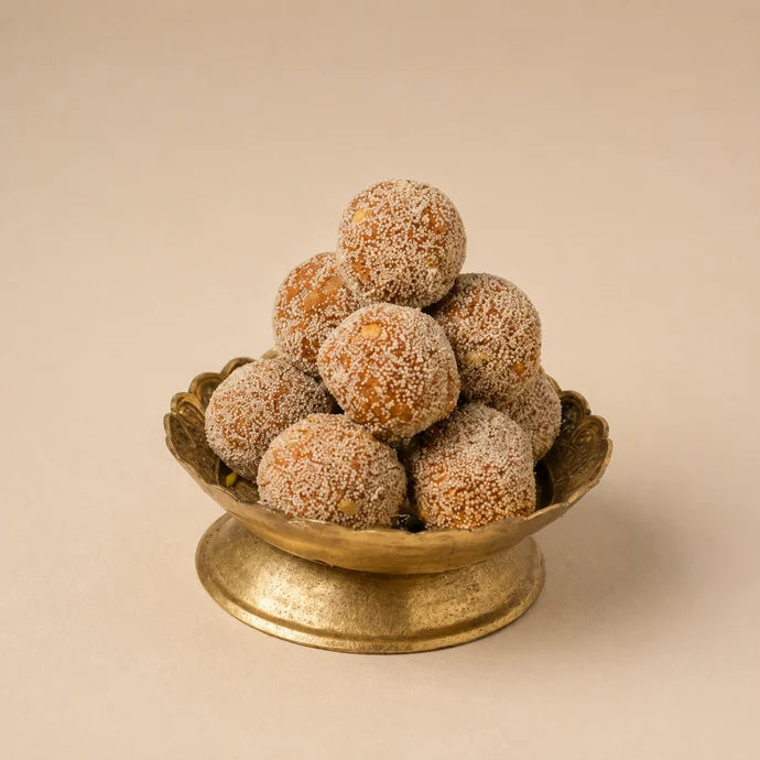MM Mithaiwala Methi Laddu stacked in a decorative brass pedestal bowl against a beige background.