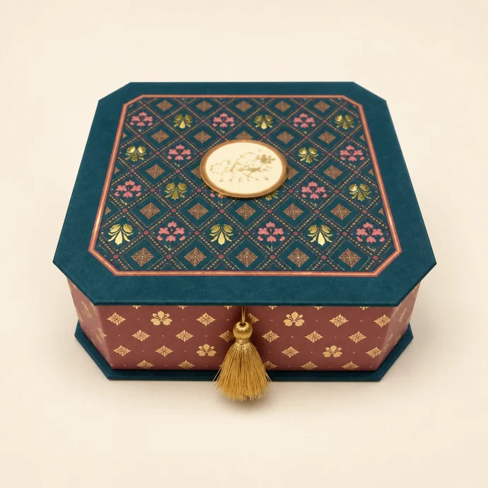 MM Mithaiwala Ornate Teal Gift Box with clipped corners, colourful geometric motifs, a central golden plaque and a tassel.
