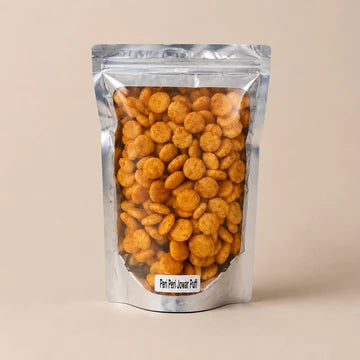 MM Mithaiwala Peri Peri Jowar Puffs in a silver resealable pouch with a clear front, against a beige background.