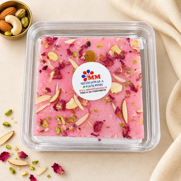 MM Mithaiwala pink Rose Ice Halwa topped with sliced nuts and rose petals in a closed clear container with a branded label.