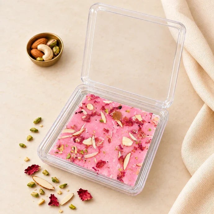 MM Mithaiwala pink Rose Ice Halwa topped with sliced nuts and rose petals in a closed clear container with a branded label.