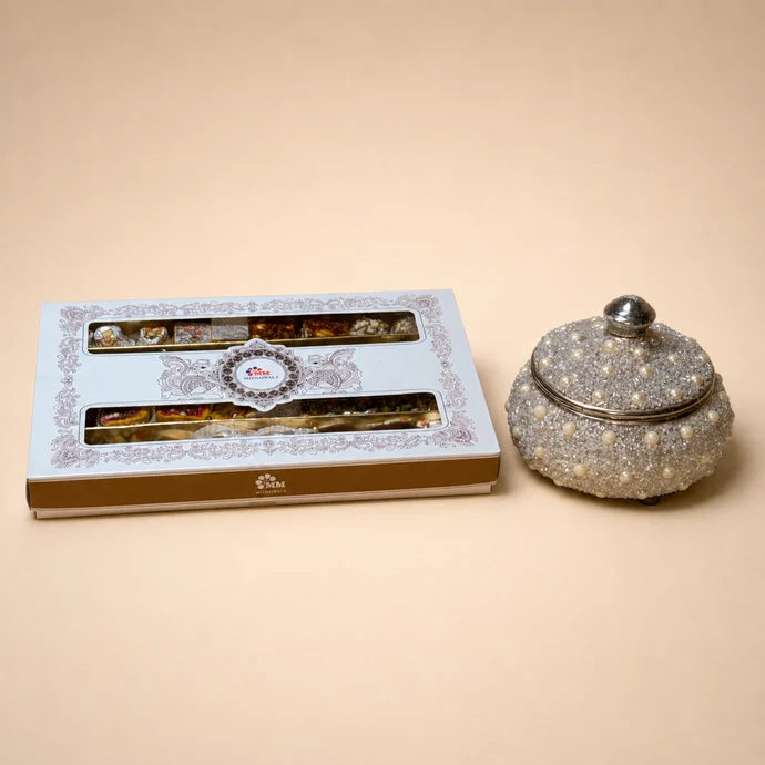 MM Mithaiwala Sahenshah mithai box with white and gold packaging and two long windows displaying assorted sweets.