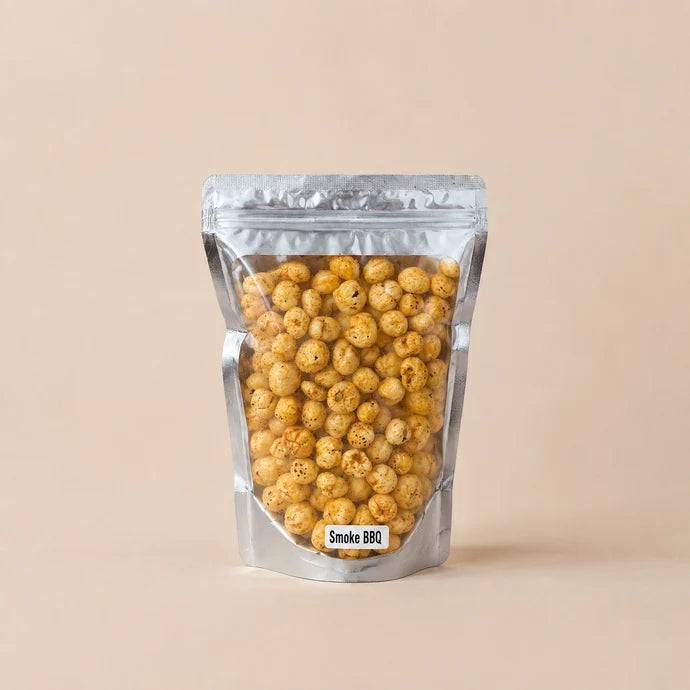MM Mithaiwala Smoke BBQ Makhana in a silver resealable pouch with a clear front, against a beige background.