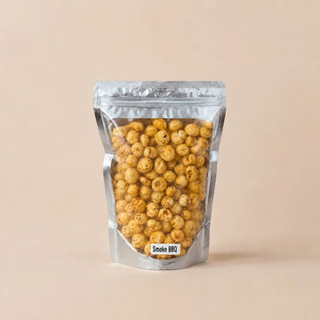 MM Mithaiwala Smoke BBQ Makhana in a silver resealable pouch with a clear front, against a beige background.