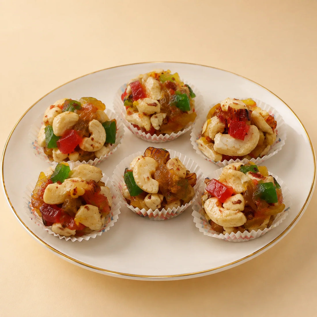 MM Mithaiwala Sugar Free Mix Fruit Laddu with colourful fruit pieces and cashews, arranged in paper cups on a white gold-rimmed plate.