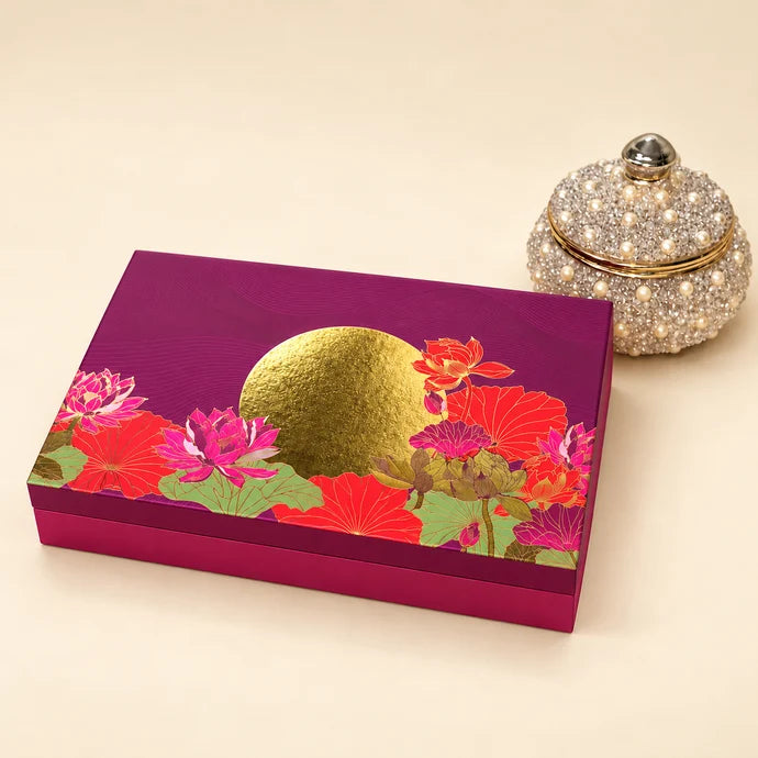 MM Mithaiwala Sunehri Box, a closed magenta gift box with colourful floral motifs and a golden circle, beside a decorative jar.
