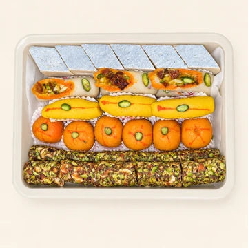 MM Mithaiwala Super Delux assorted mithai tray with silver-leaf kaju katli, colourful sweets and nut-coated rolls arranged in neat rows.
