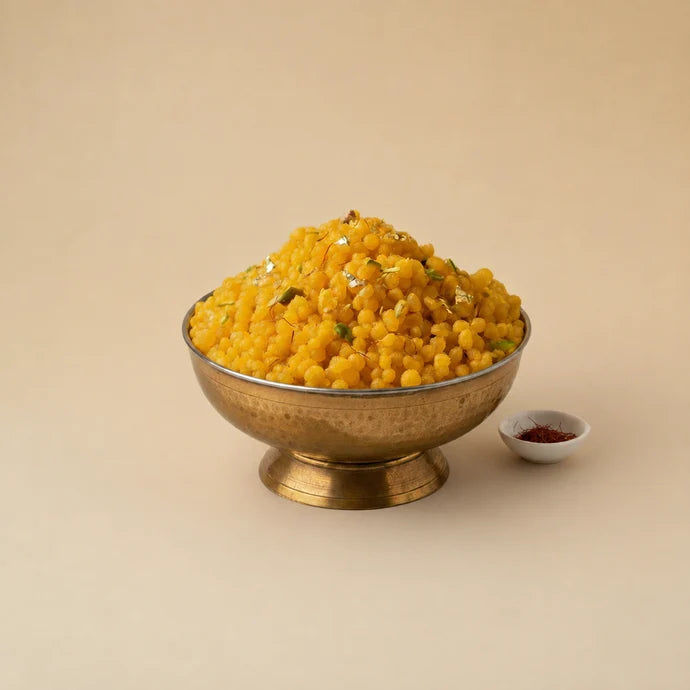 MM Mithaiwala sweet boondi garnished with nuts and silver leaf in a brass bowl.